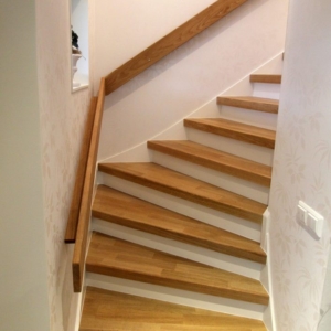 Stängd trappa i Ek 3-stav med vitmålade sättsteg och handledare.